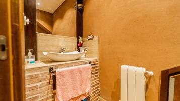 Un bagno con un lavabo a incasso bianco, uno specchio, un porta asciugamani e un termosifone.