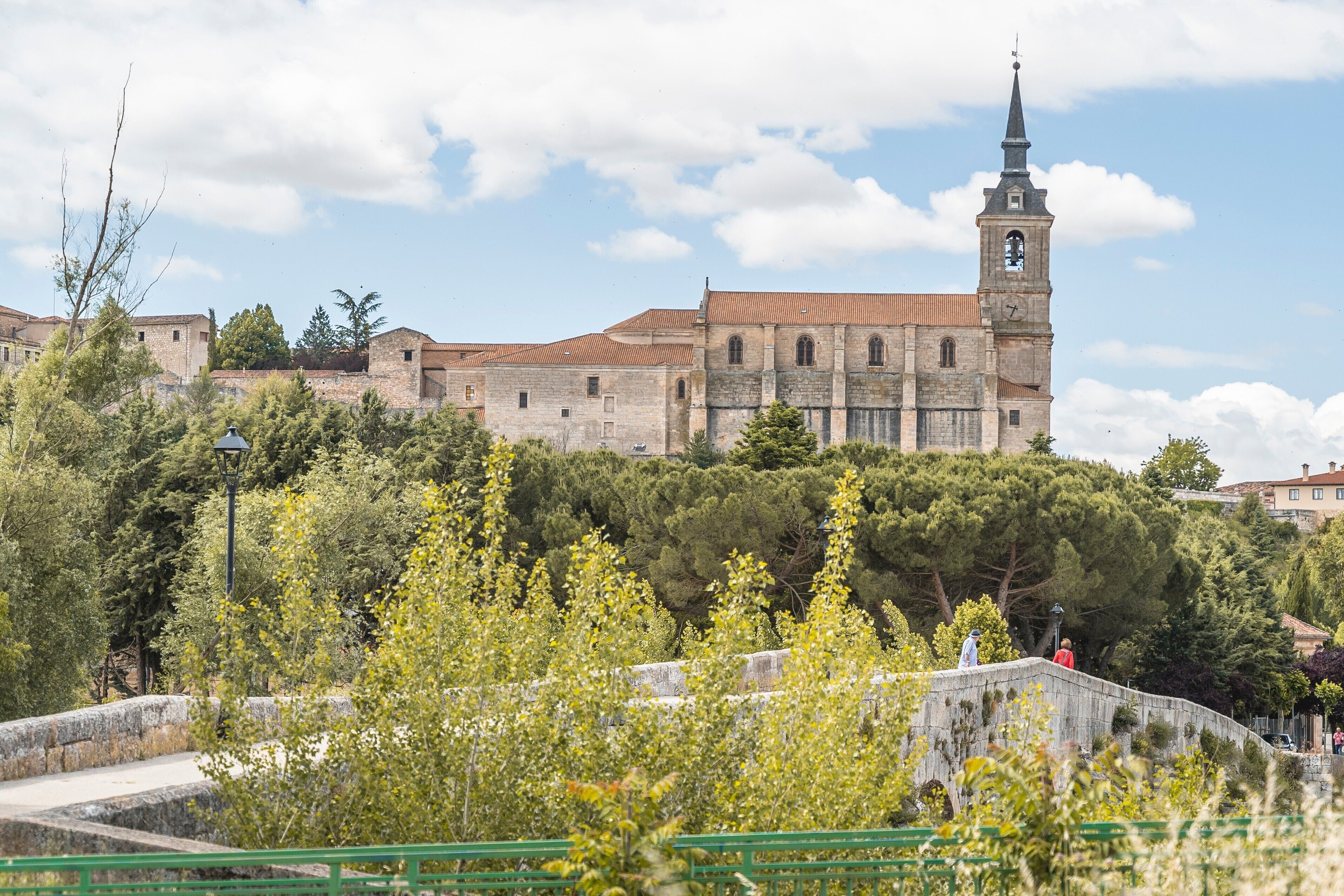 Un edificio storico con una torre imponente e un muro in pietra sullo sfondo.