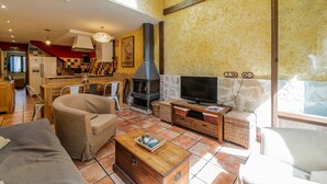 A living room with a sofa, a coffee table, a TV, a fireplace, and a kitchen area.