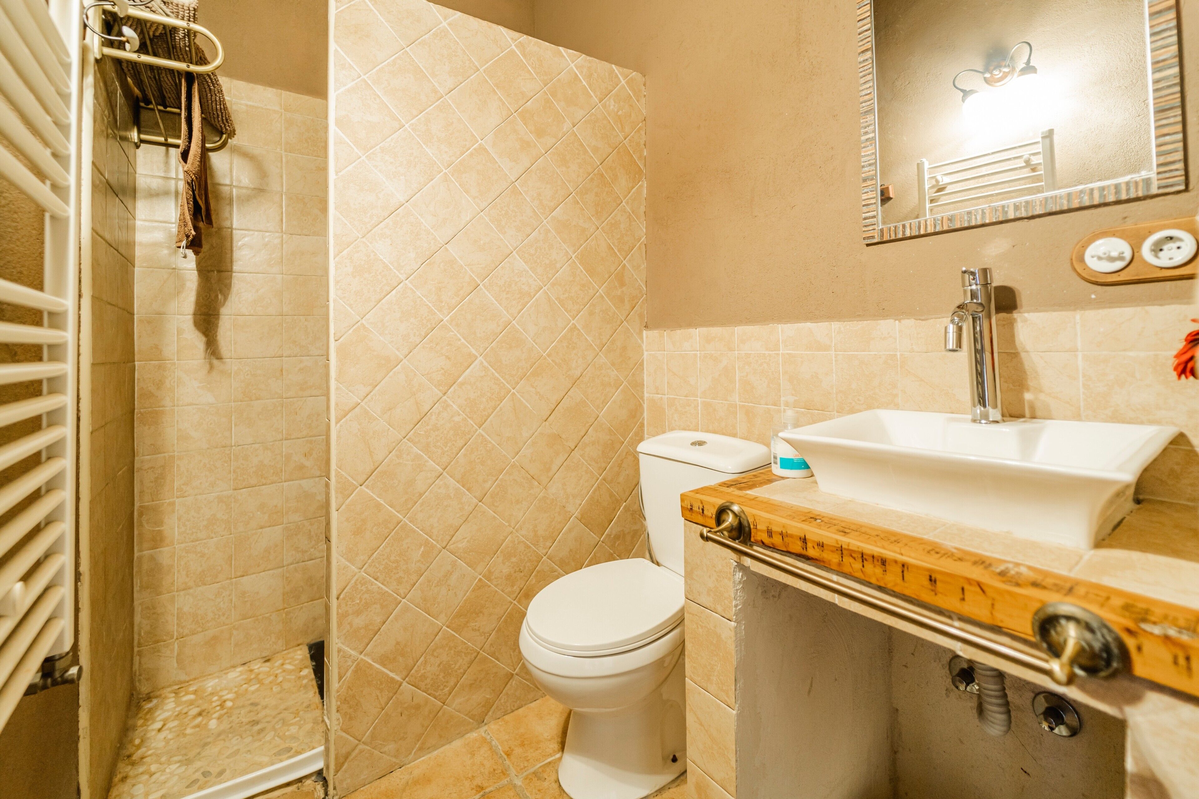A bathroom with a toilet, sink, mirror, and towel rack.