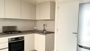 Una cucina moderna con elettrodomestici in acciaio inossidabile, mobili bianchi e forno integrato.