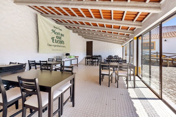 A spacious indoor area with tables and chairs, a large banner on the wall, and a view through large windows.