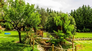 A garden with a wooden fence, a stone pathway, and various green plants. - Apartment 'Casa Retiro' with Shared Pool, Wi-Fi and Air Conditioning (Azambuja)