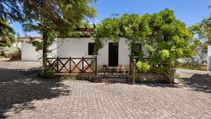 A white building with a wooden gate, a cobblestone courtyard, and a tree in front. - Apartment 'Casa Retiro' with Shared Pool, Wi-Fi and Air Conditioning (Azambuja)
