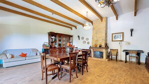A dining area with a wooden table and chairs, a sofa, and a fireplace. - Apartment 'Casa Retiro' with Shared Pool, Wi-Fi and Air Conditioning (Azambuja)