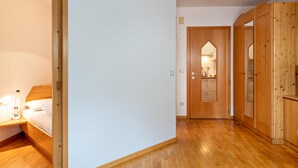 A bedroom with a wooden bed, a bedside table with a lamp, and a wardrobe.