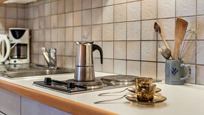 A kitchen with a coffee maker, a kettle, a mug, and a spoon holder on the counter.