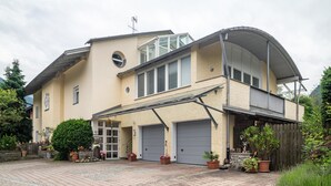 Ein zweistöckiges Haus mit überdachter Veranda, Garage und kleinem Garten mit Topfpflanzen.