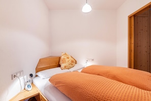 Un dormitorio con una cama, una mesita de noche, una lámpara y un armario de madera.