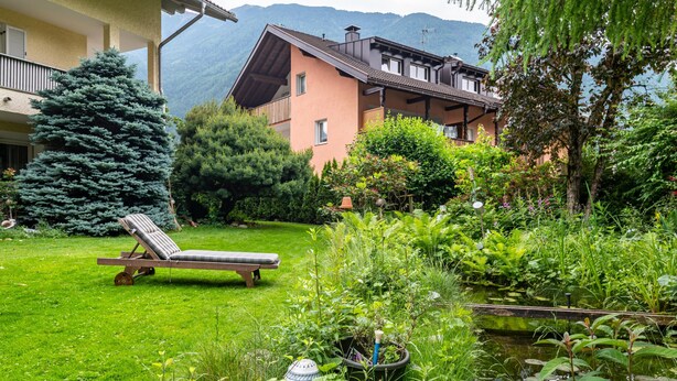 Ein Garten mit Pool, Liegestuhl und einem Gebäude mit Balkonen.