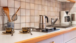 Eine Küchenarbeitsplatte mit Kaffeemaschine, zwei Tassen und einem Löffel.