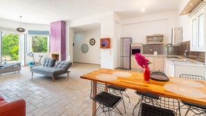 Una cucina moderna con zona pranzo, divano e vista sul verde.