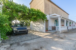 Un edificio con ingresso in pietra, un portico coperto con colonne e un veicolo parcheggiato.