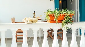 Un espace repas comprenant une table, des chaises, une plante en pot, une bouteille et un verre.