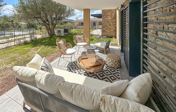 Relax on the patio with a comfortable sofa, wicker chair, and round table.