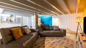 A modern living room with a sectional sofa, a patterned rug, and a television on a stand.