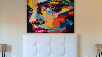 A room with a large, colorful abstract painting on the wall, a tufted headboard, and two floor lamps.