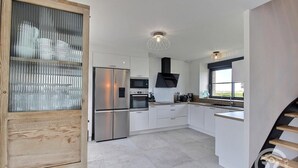 A modern kitchen with white cabinets, stainless steel appliances, and a built-in oven. - Kergonet - Plougrescant (PLOUGRESCANT)