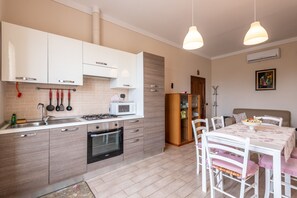 Une cuisine moderne équipée d’un four à micro-ondes, d’une cuisinière et d’un four, un coin repas avec une table et des chaises, et une bibliothèque.