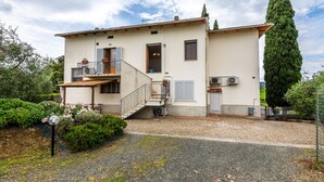 Ein zweistöckiges Gebäude mit Balkon, Treppe und Garten.
