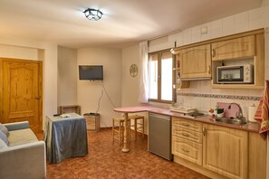 Une cuisine compacte avec des meubles en bois, un four à micro-ondes, un évier et un petit coin repas comprenant une table et des chaises.