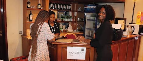 Una zona de bar con un cartel que dice 'NO CREDIT PLEASE', estantes con botellas y un refrigerador de Pepsi.