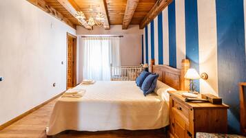 Een slaapkamer met een bed, houten hoofdbord, nachtkastje met lamp en uitzicht op een balkon.