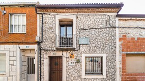 Un bâtiment en pierre avec une porte en bois, une fenêtre ornée d’une grille métallique et une enseigne sur laquelle on peut lire « El Pecho ».