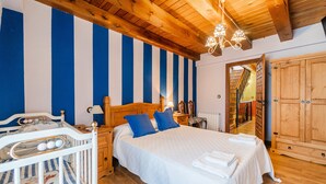 Une chambre à coucher avec un grand lit, une tête de lit en bois, des tables de chevet, une commode, une armoire et un berceau.
