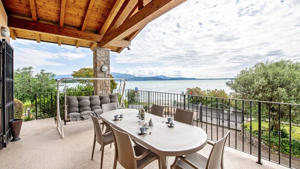 A covered outdoor dining area with a view of the lake and mountains. - Happy Villa Apartment with Lake View, Private Terrace and Wi-Fi (San Felice del Benaco)