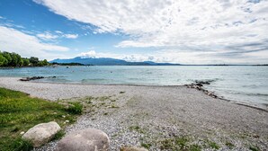 A pebbled beach with a clear sky and distant mountains. - Happy Villa Apartment with Lake View, Private Terrace and Wi-Fi (San Felice del Benaco)