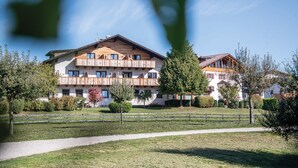 Un hotel de varios pisos con balcones de madera, un sendero empedrado y abundante vegetación.