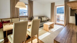A modern living room with a sofa, dining table, chairs, and a TV. - Apartment 'Aparment Family 6' with Mountain View, Shared Garden and Wi-Fi (Fié allo Sciliar)