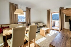 A modern living room with a sofa, dining table, chairs, and a TV.
