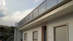 Un edificio moderno con un balcón, una escalera y una pequeña entrada con puerta.