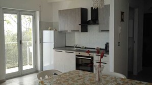 Una cocina moderna con armarios blancos, una mesa de comedor con mantel floral y una araña.