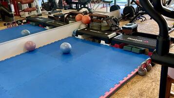Ein Fitnessraum mit Trainingsgeräten, Matten und Gewichten.