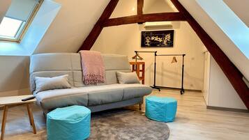 Slaapkamer in loftstijl met een slaapbank, poefs, een vloerkleed en een kledingrek.