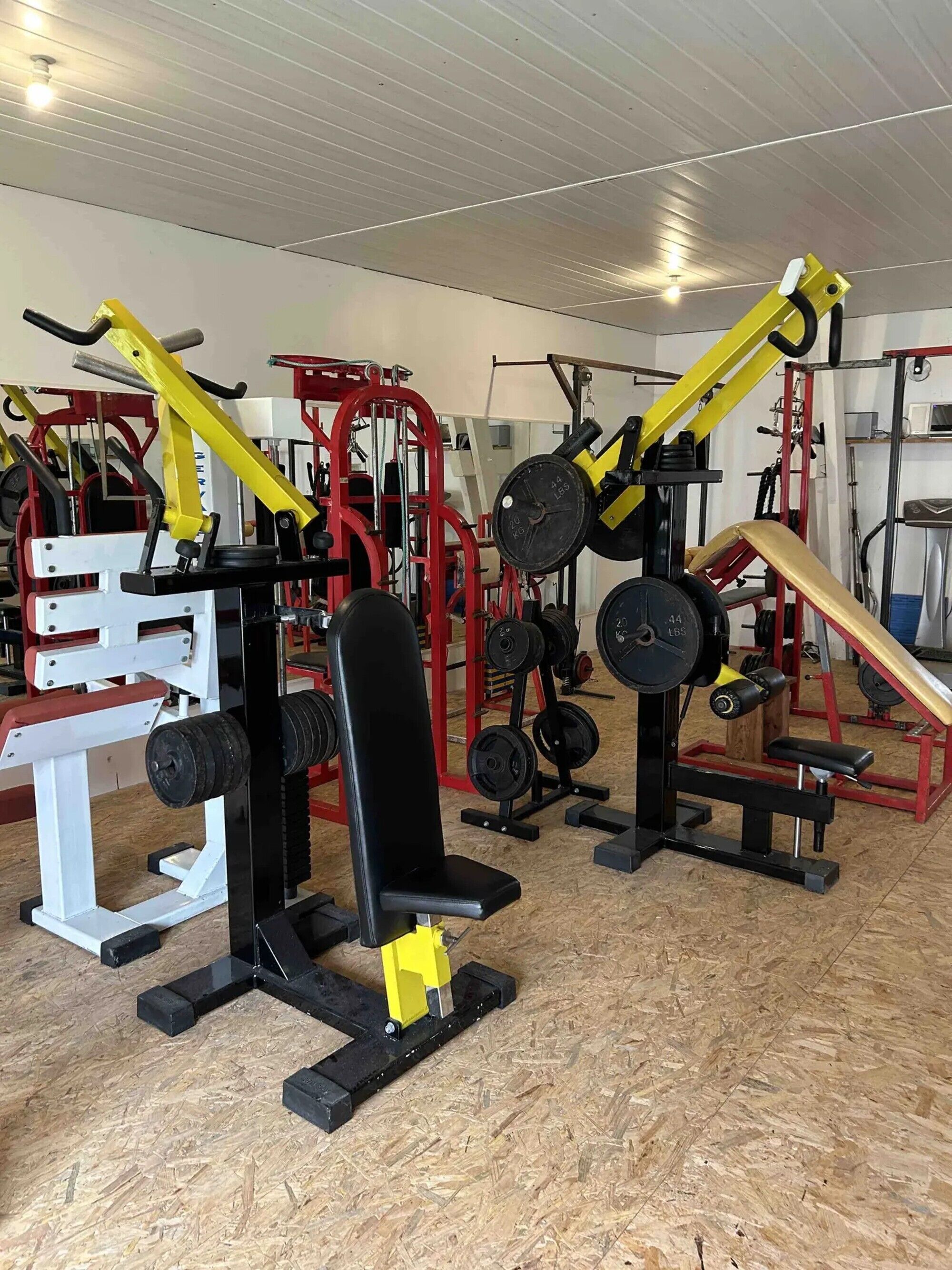 Un gimnasio con diversos equipos de ejercicio, incluidas pesas y máquinas de levantamiento.