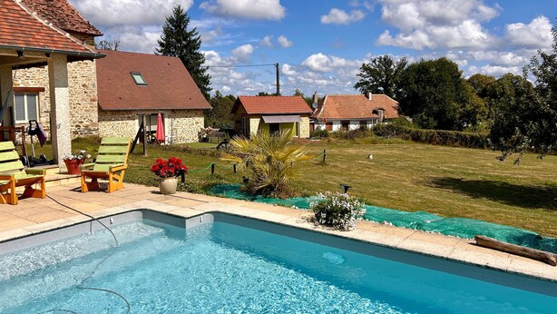 A swimming pool with a stone house, a lawn, and a clear sky. - Charming Fitness & Wellness Gîte with Shared Pool (Masseret)