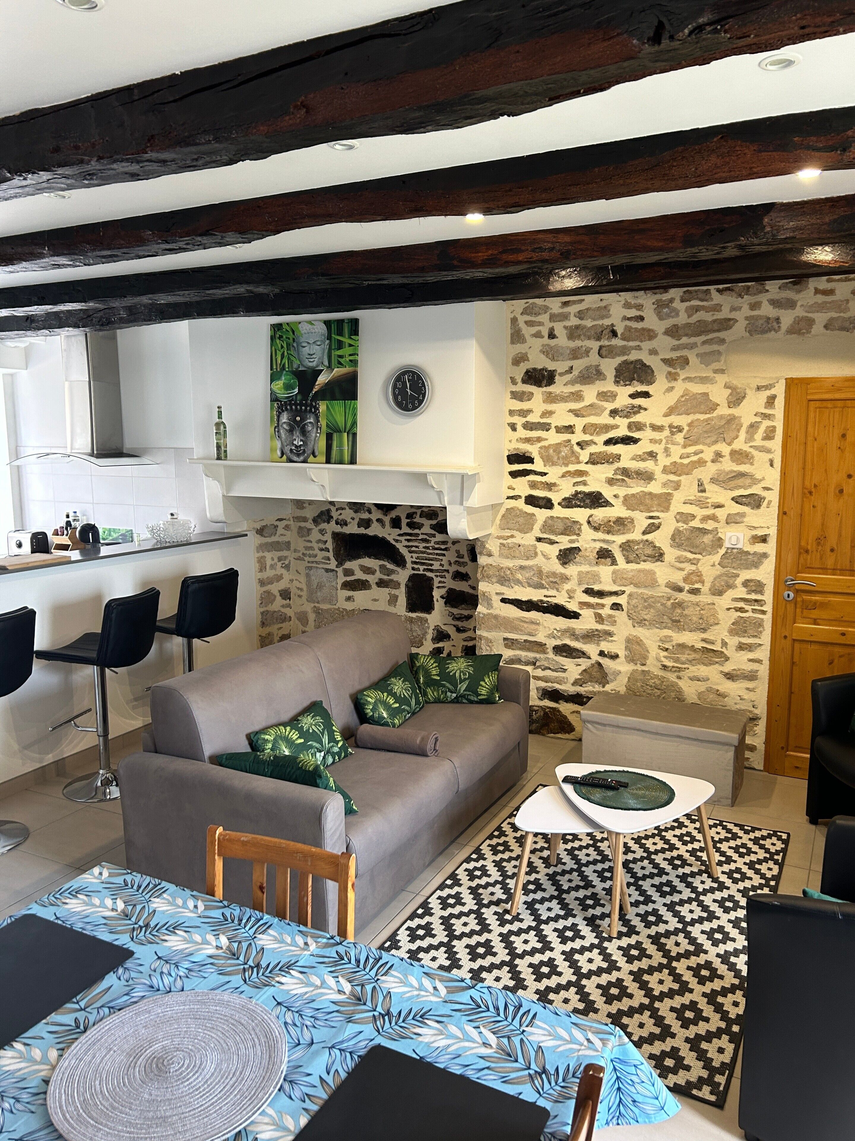 Een gezellige woonkamer met een stenen muur, een open haard, een bank en een eethoek met stoelen.