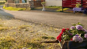 A rural house with a stone wall, a wooden bench, and a wheelbarrow with flowers. - Charming Fitness & Wellness Gîte with Shared Pool (Masseret)