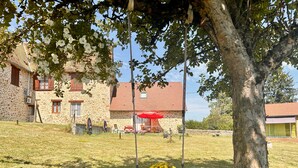 A stone building with a red roof, a swing with flowers, and a grassy yard. - Charming Fitness & Wellness Gîte with Shared Pool (Masseret)
