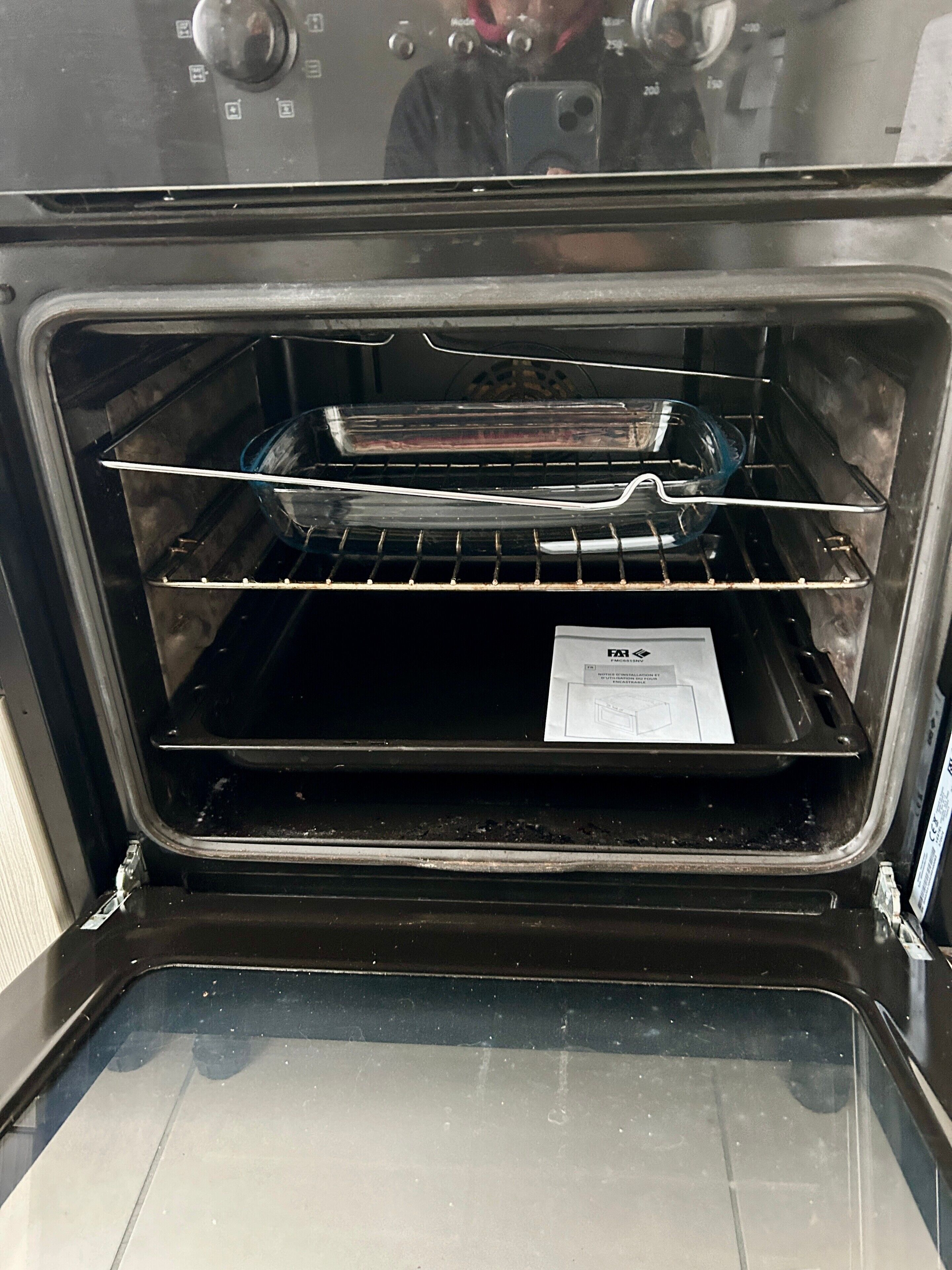 Un horno abierto con una rejilla metálica y un folleto de instrucciones blanco en su interior.