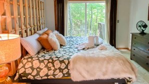 A bedroom with a bed, pillows, a bedside lamp, a dresser, and a window with a view of greenery. - Secluded Jackson Family Escape w/ Views & Deck (Jackson)
