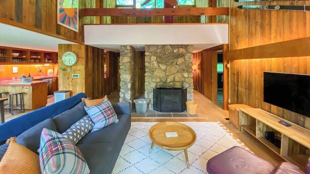 A cozy living room with a stone fireplace, a large TV, and a ceiling fan. - Secluded Jackson Family Escape w/ Views & Deck (Jackson)