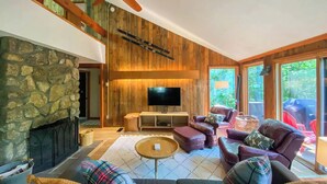 A cozy living room with a stone fireplace, wooden walls, and a ceiling fan. - Secluded Jackson Family Escape w/ Views & Deck (Jackson)