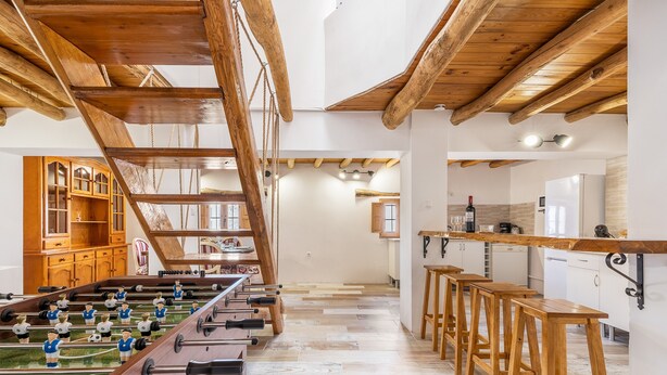 A spacious room with a foosball table, wooden bar stools, and a kitchen area. - Holiday Home "Casa Rústica – Your Retreat with Terrace and Mountain Views" (Vélez de Benaudalla)