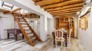 A wooden staircase, a dining table with chairs, and a wooden cabinet in a room with wooden flooring and a sloped ceiling. - Holiday Home "Casa Rústica – Your Retreat with Terrace and Mountain Views" (Vélez de Benaudalla)