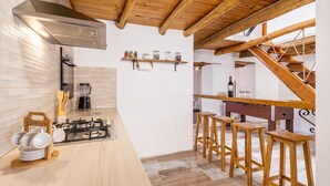 A modern kitchen with a gas stove, wooden stools, and a bar area with stools. - Holiday Home "Casa Rústica – Your Retreat with Terrace and Mountain Views" (Vélez de Benaudalla)